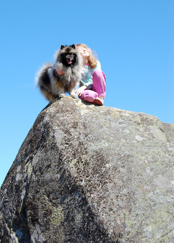 Hund och flicka på stor sten.